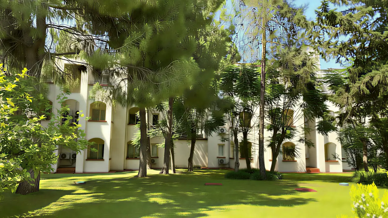 Elewacja budynku Queens Park Resort Goynuk otoczona zielenią i drzewami