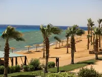 Plaża z palmami i parasolami w Retac Qunay Dahab Resort & Spa