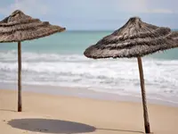Słomiane parasole na plaży w Royal Tulip Taj Sultan 