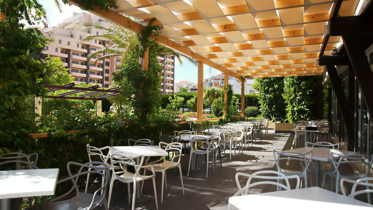 Taras restauracyjny z białymi stolikami w RR Club Amarilis