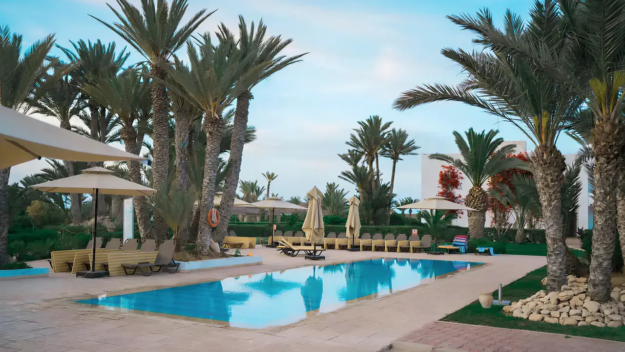 Basen z leżakami i palmami w Seabel Rym Beach Club